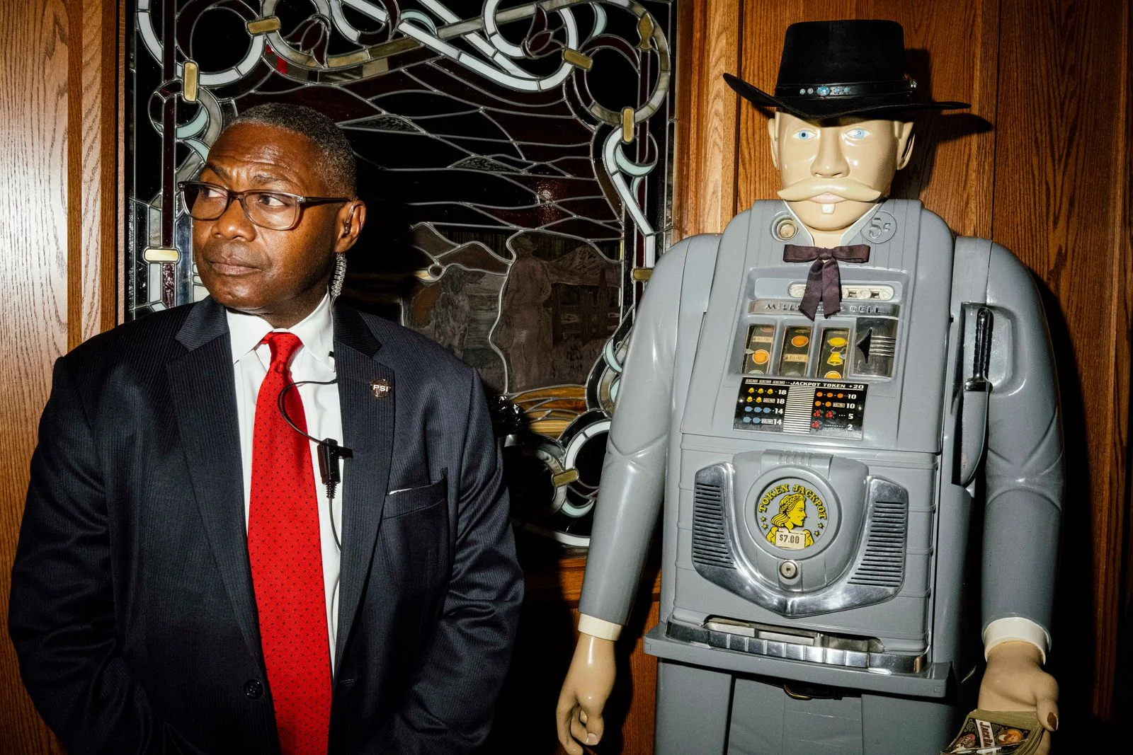 A security standing near the wall of a venue next to a cowboy ATM