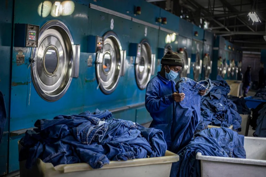MASERU, LESOTHO - JULY 3: A garment factory worker checks denim products from an industrial dryer on July 3, 2025 in Ha Thetsane Industrial Area in Maseru, Lesotho. Lesotho garment manufacturer Presitex makes denim and exports exclusively to the South African jeans market. It is the largest garment factory in Lesotho, employing over 2000 workers. (Photo by Per-Anders Pettersson/Getty Images)