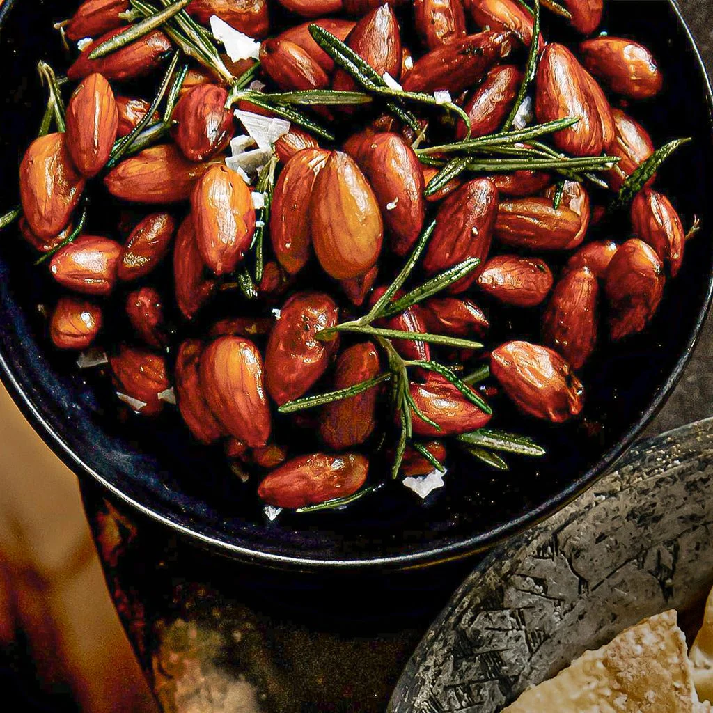 A bowl of rosemaryfried almonds topped with flaky sea salt.