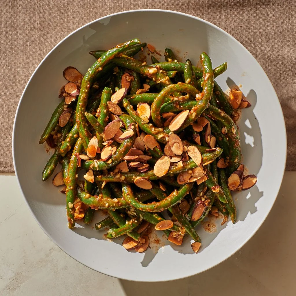 Green Beans With Almond Butter Sauce on a white plate on a cloth background