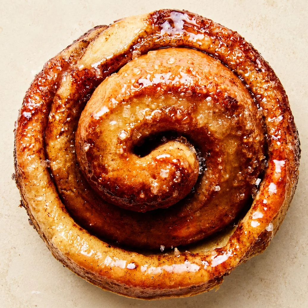 A single morning bun in a tight spiral on a stone surface.