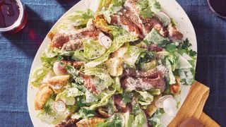 Platter of sliced ribeye steak salad with romaine lettuce toasted pita crumbled feta sliced radishes fresh herbs and...