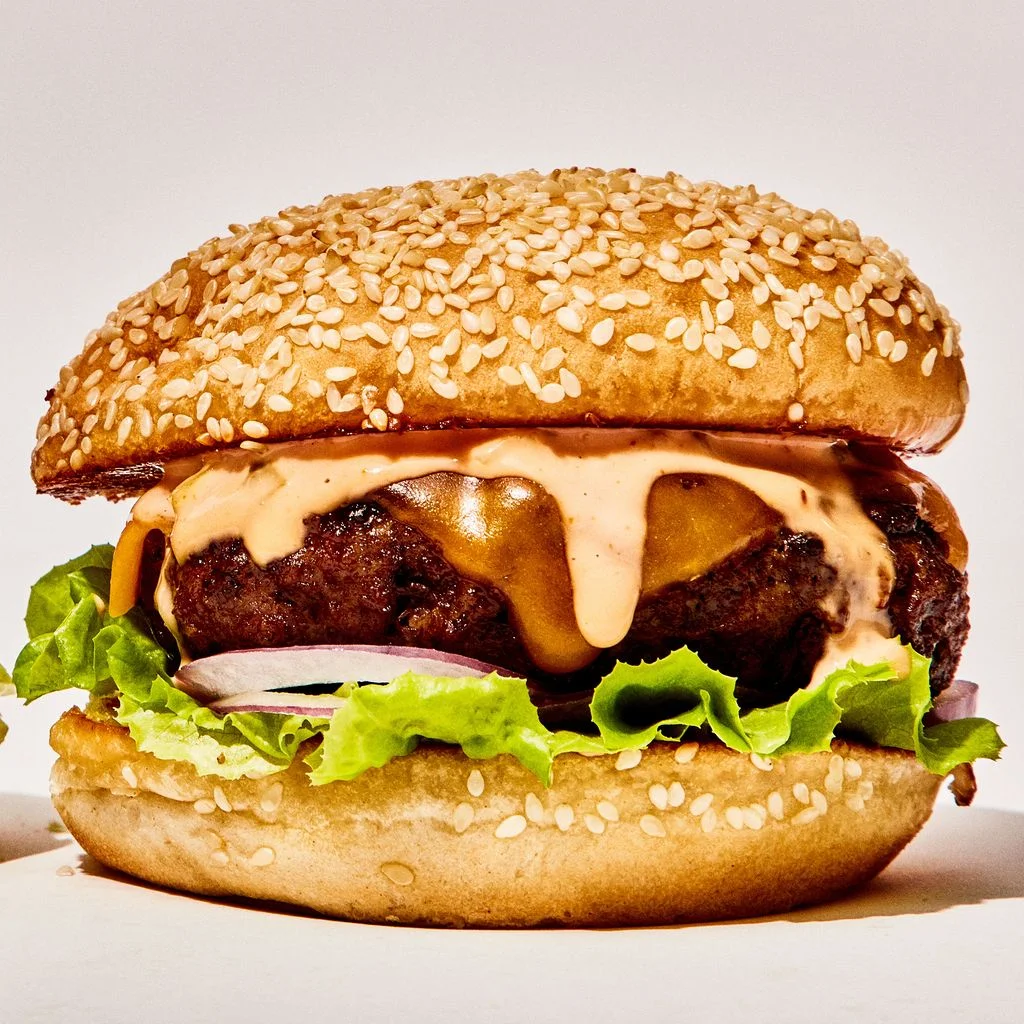 Two cheeseburgers on seeded buns with lettuce red onion and secret sauce.