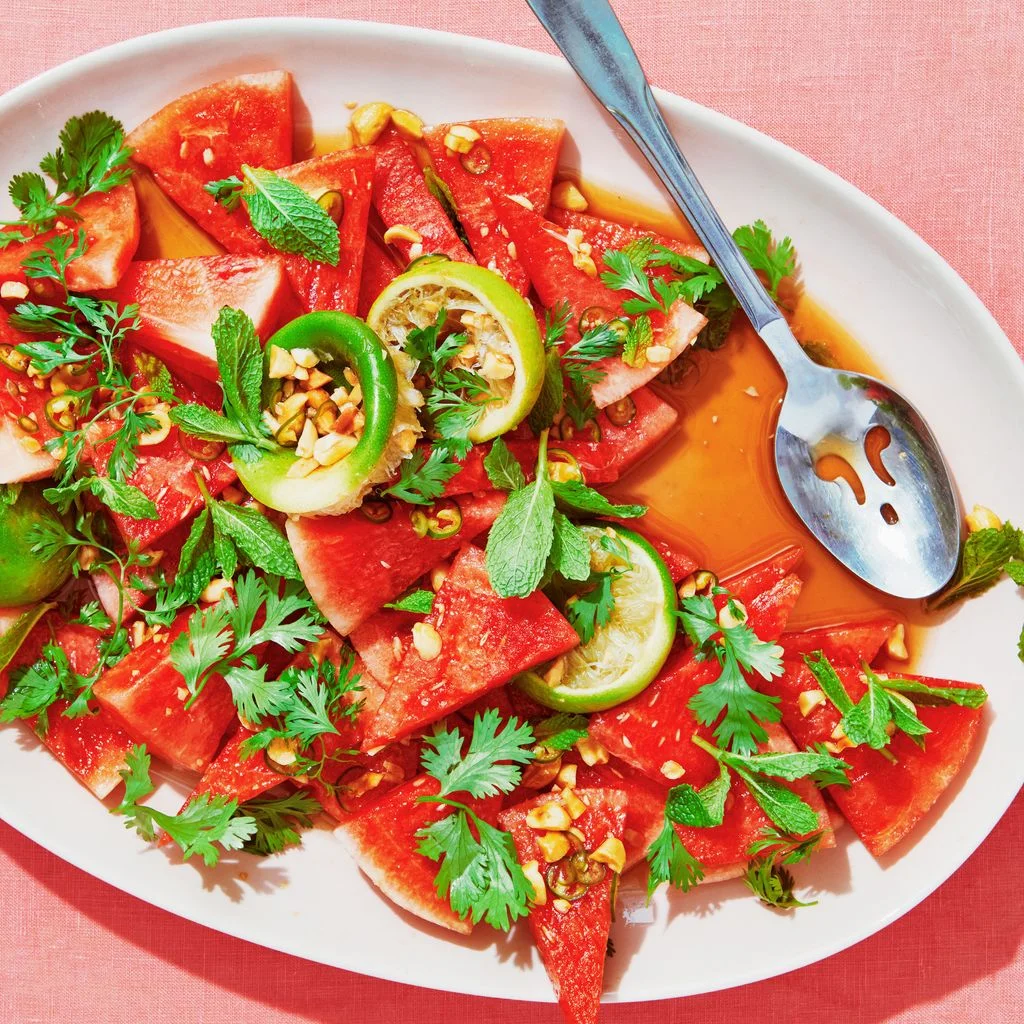 Watermelon cut into triangles crushed peanuts and limes tossed in fish sauce lime juice brown sugar and salt and topped...