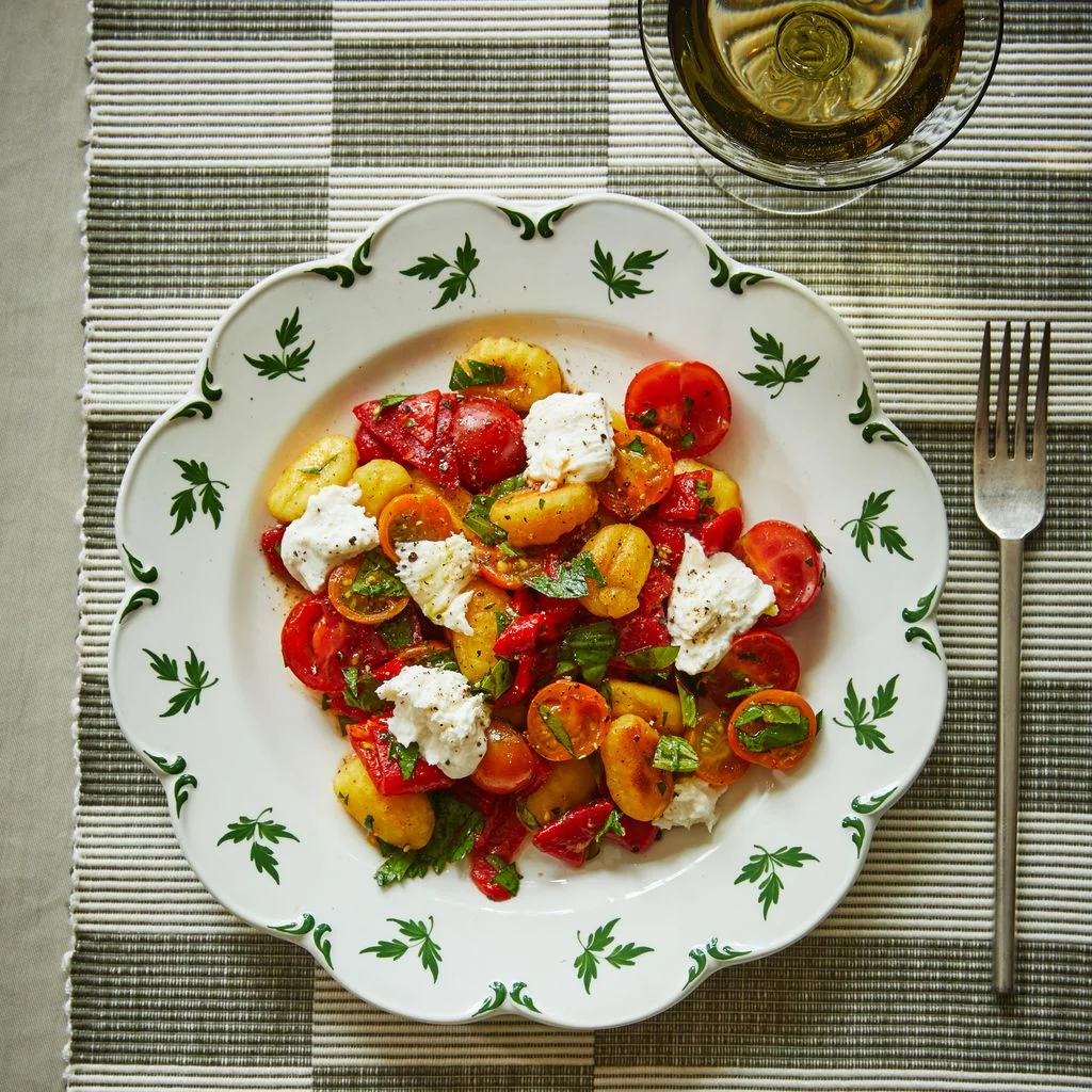 Crispy gnocchi tomatoes shredded mozzarella and torn basil leaves on a plate.