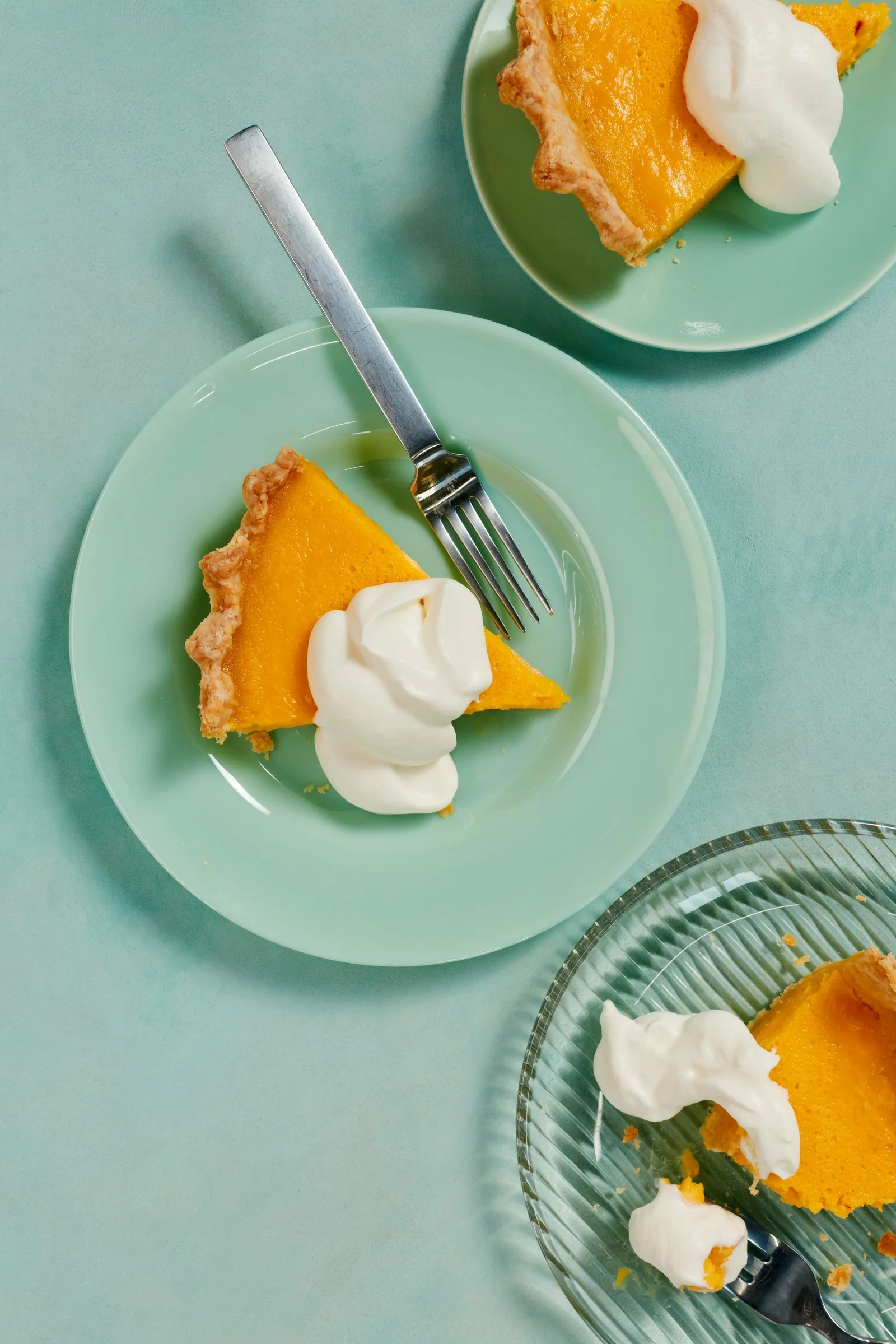 Three slices of golden saffron buttermilk lemon pie on pastel green plates.