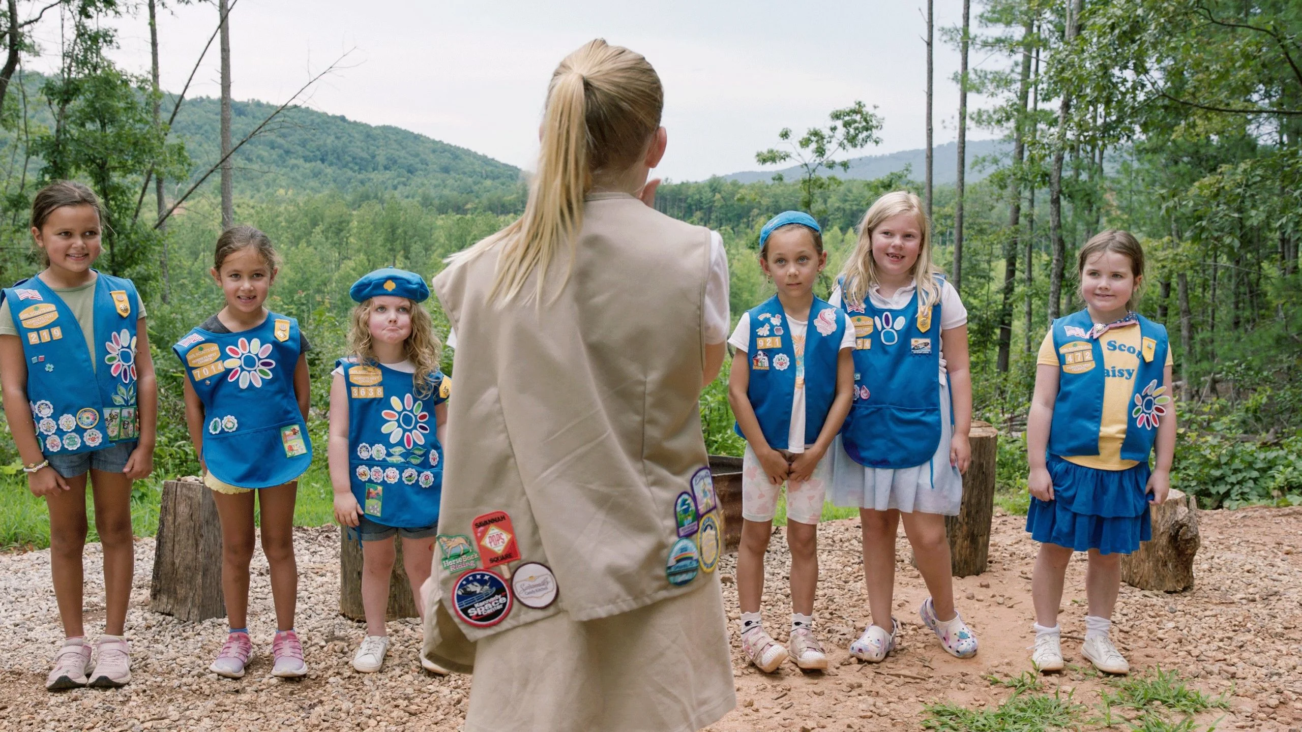 A group of young girl scouts standing in front of the troop leader.