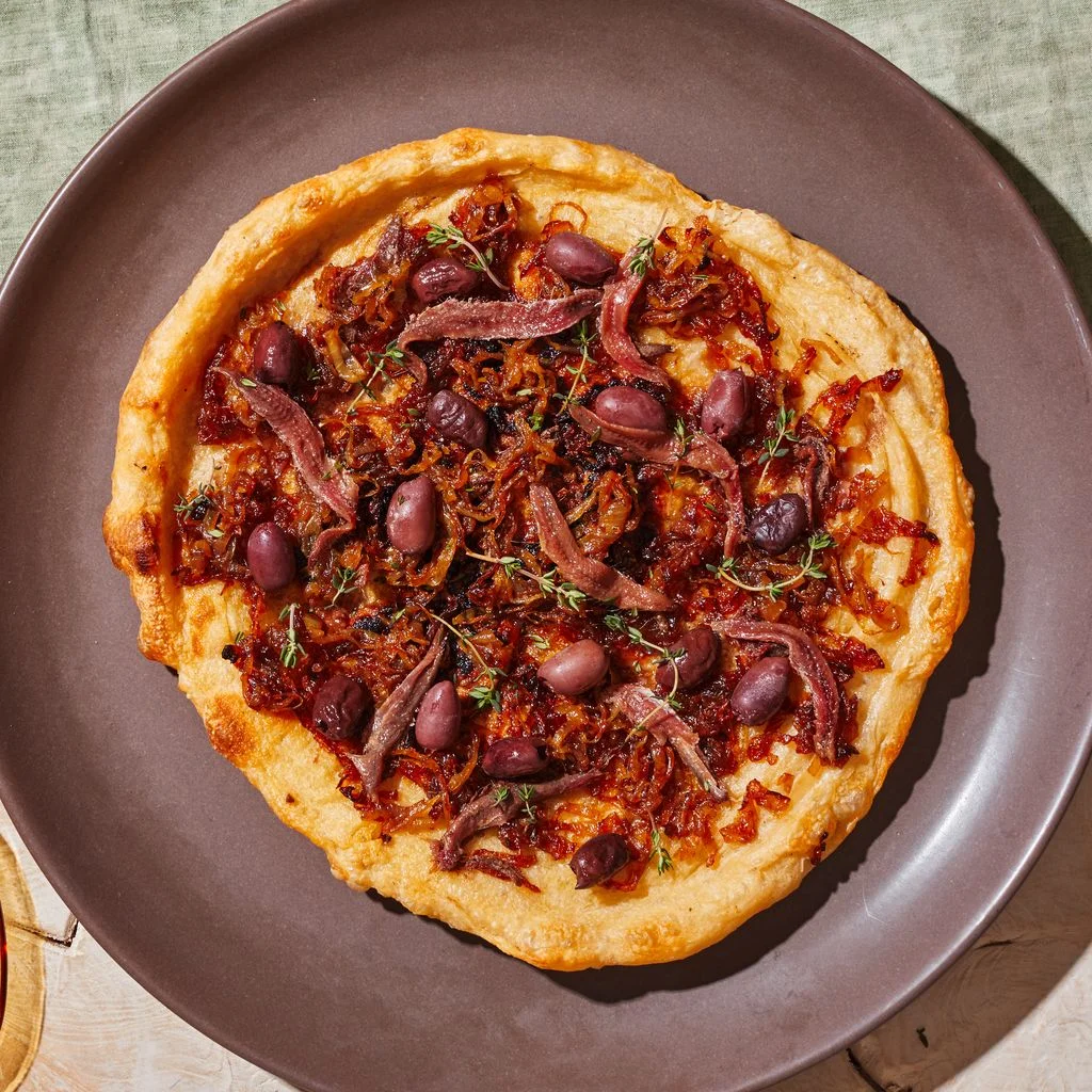 A pissaladière made with storebought pizza dough Kalamata olive anchovy fillets and caramelized Vidalia onions.