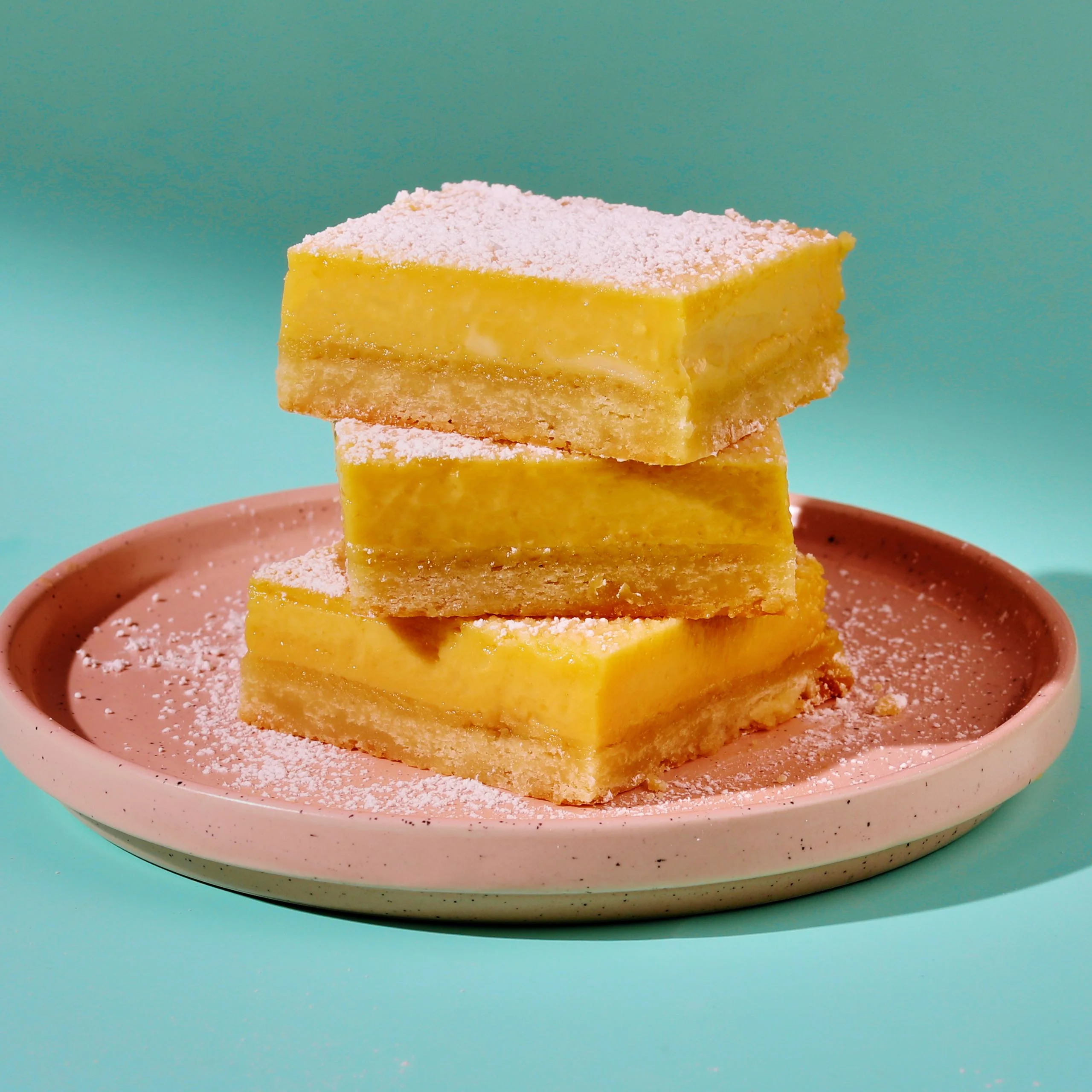 3 stacks of Lemon Bars on a pink plate