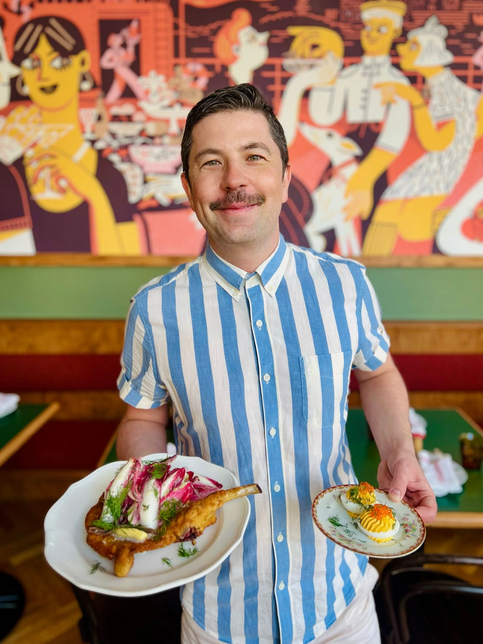 Pierogi Boys cofounder Andrzej Kinczyk holding Jajka Faszerowane and Schabowy at their Ridgewood location.