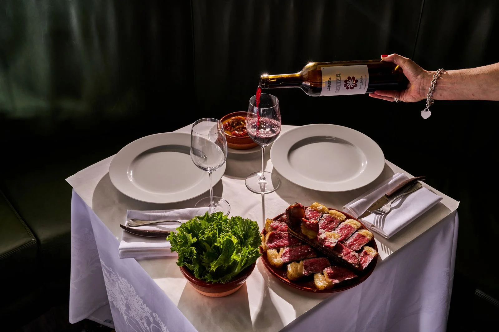 Pork chops greens and red wine on a dining table at Bartolo in New York City.