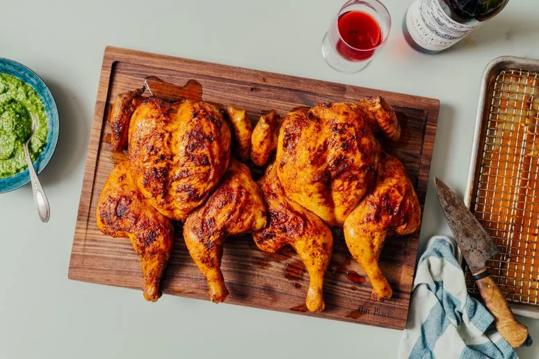 2 roast chickens on a wooden cutting surface