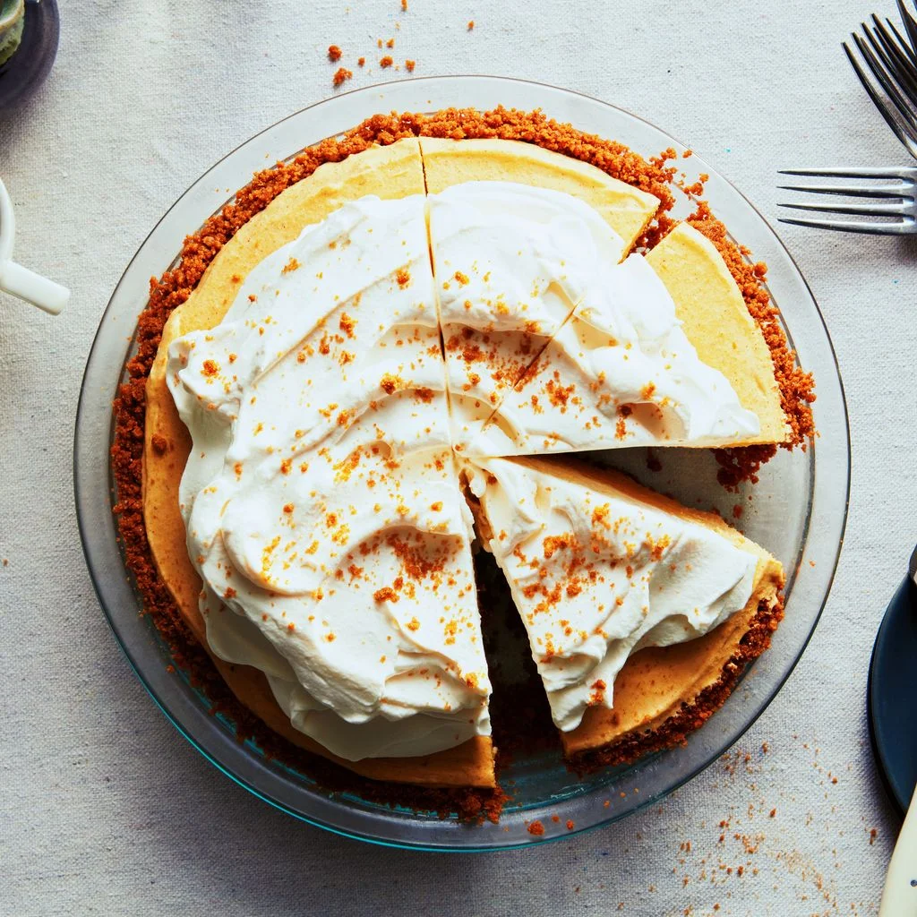 Pumpkin silk pie topped with whipped cream and Biscoff cookie crumbs and cut into pieces.