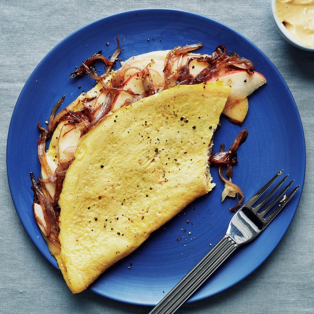 An omelette filled with caramelized onions sliced Fuji apples and fontina cheese and served with Dijon mustard.