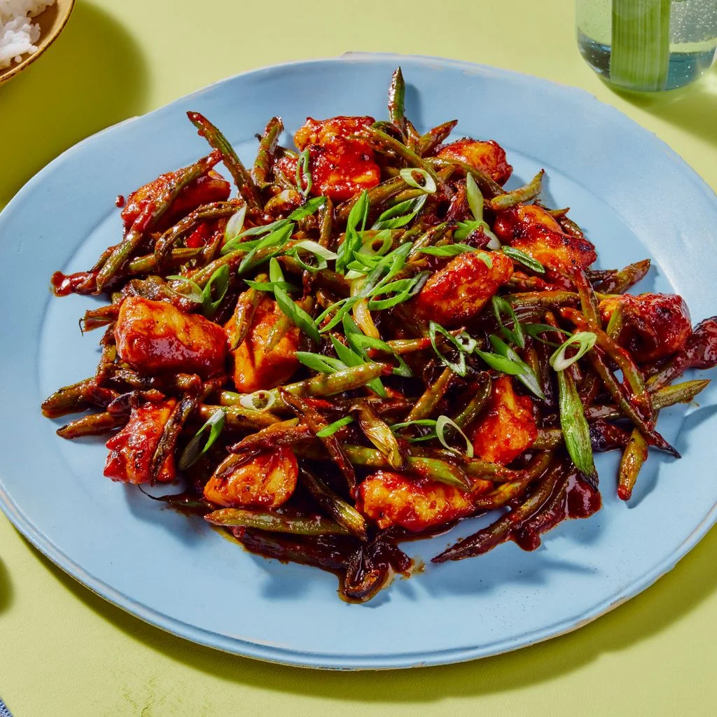 Gochujang Chicken and Scallion Stir Fry  on a blue plate and on a green background