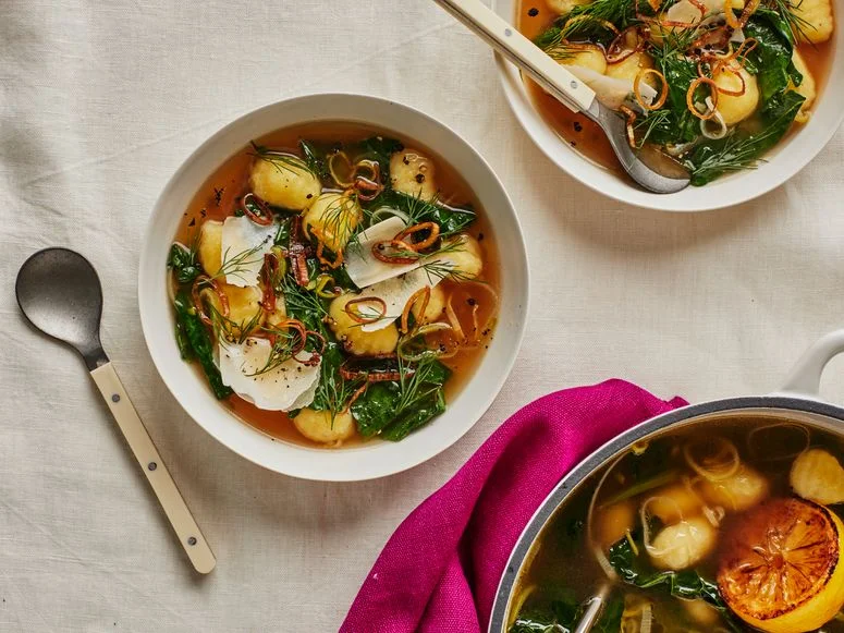 GnocchiLeek Soup With Greens in a white bowl on a white surface