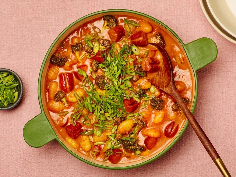 Creamy Gochujang Pasta in a a green dutch oven on a pink fabric