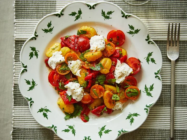 Crispy gnocchi tomatoes shredded mozzarella and torn basil leaves on a plate.
