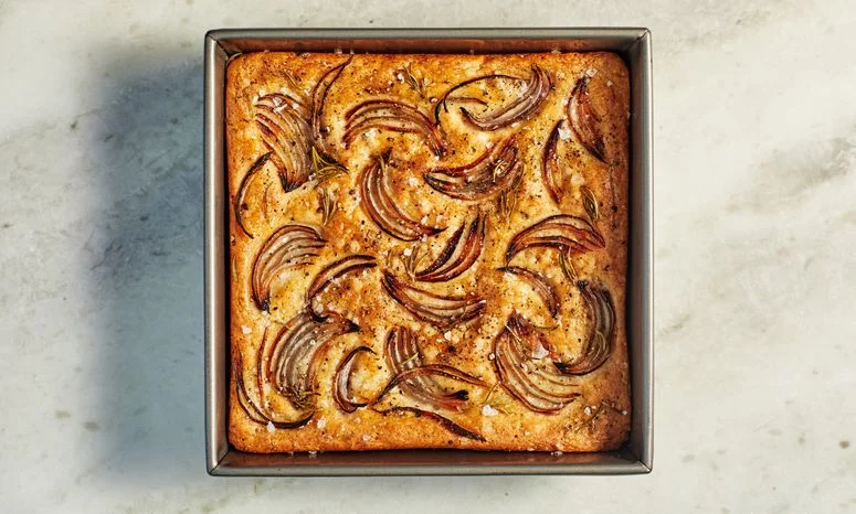 Red Onion and Rosemary Focaccia in a pan on a marble surface