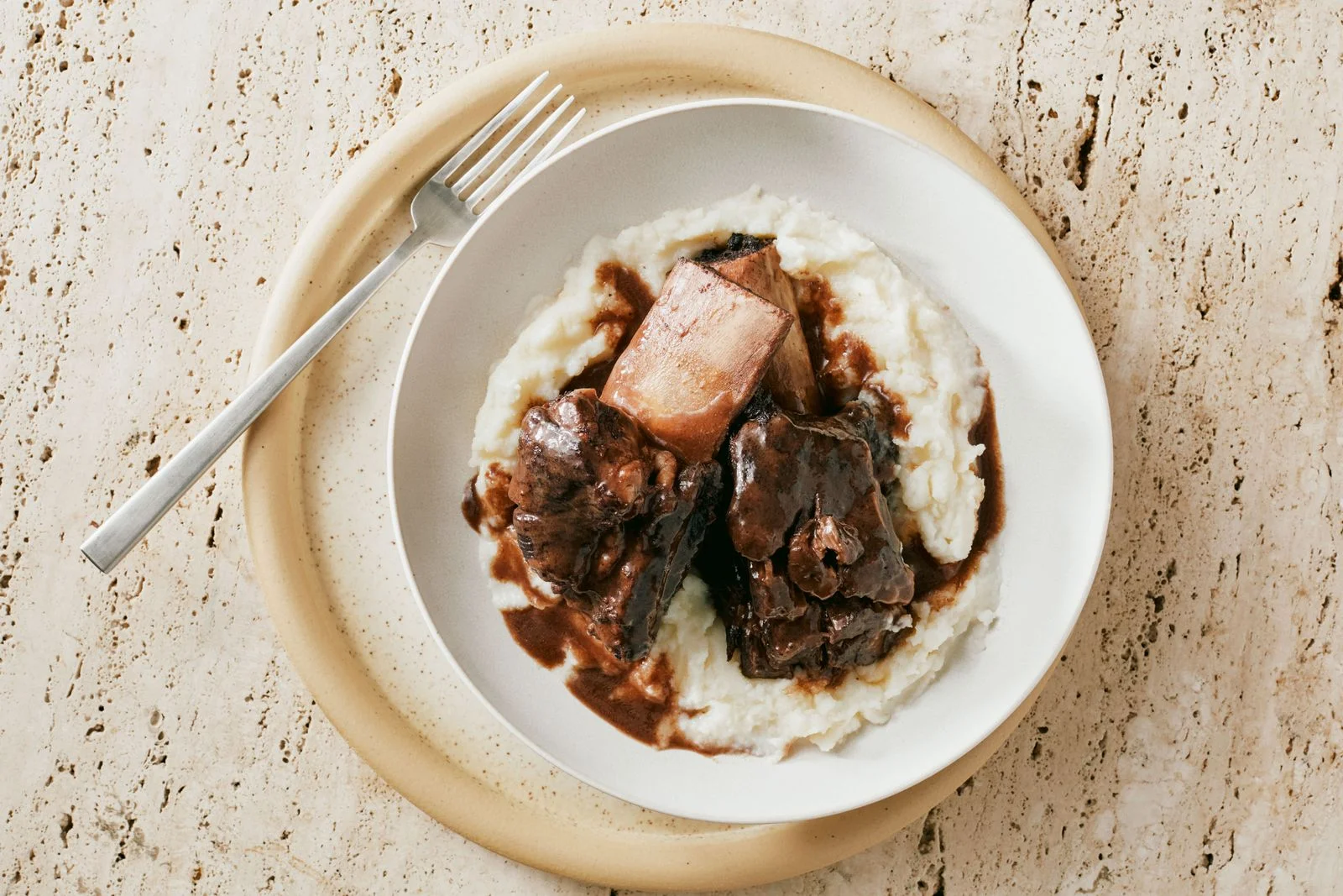 Two short ribs braised in red wine and served over a bed of mashed potatoes.