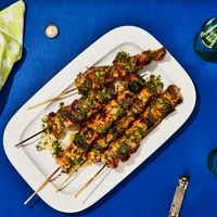 Charred Sprite-Grilled Chicken Skewers served on a platter with herb sauce.