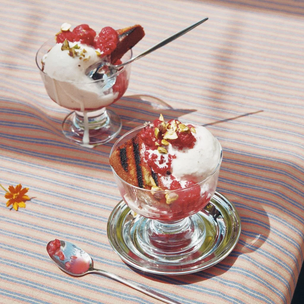 Sliced grilled poundcake in dessert coupes with vanilla ice cream macerated raspberries in Cointreau and topped with...