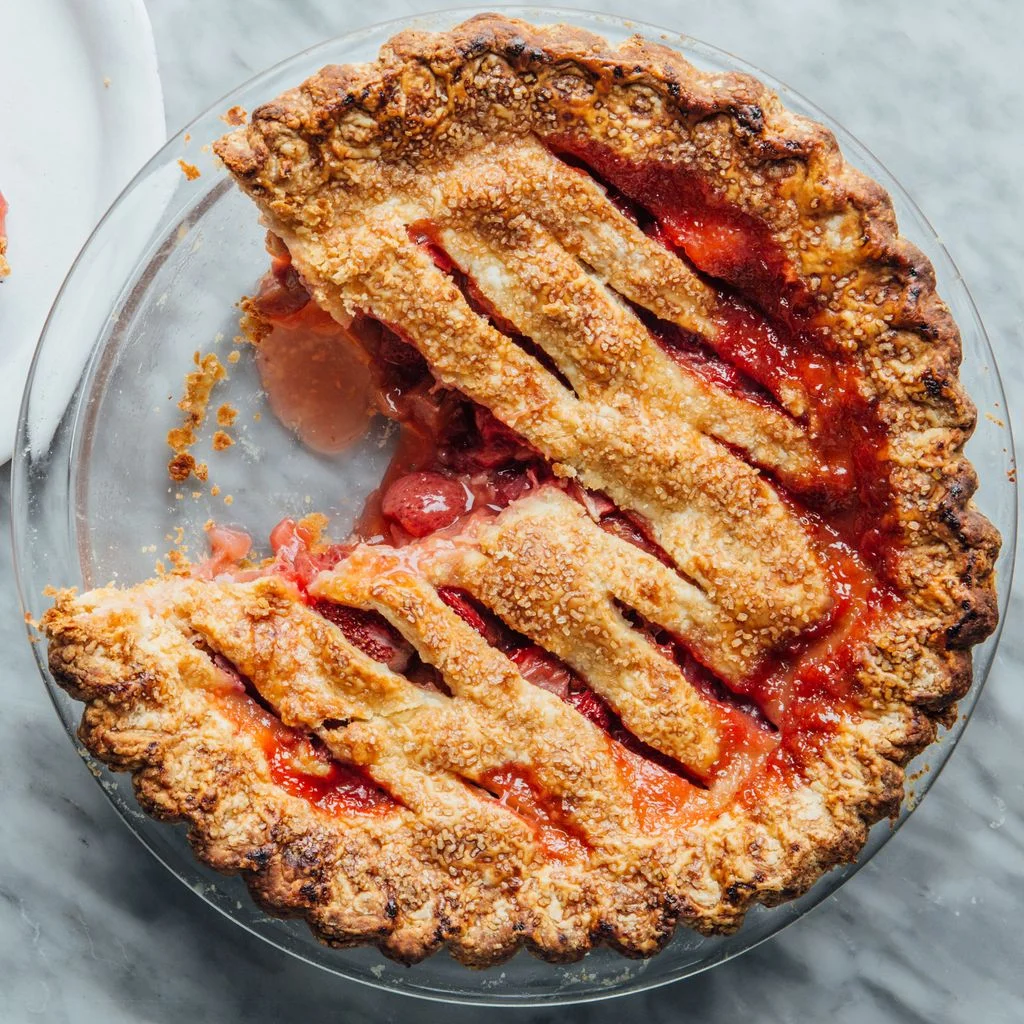Topdown view of a strawberry rhubarb pie with one slice cut out and removed to a plate.
