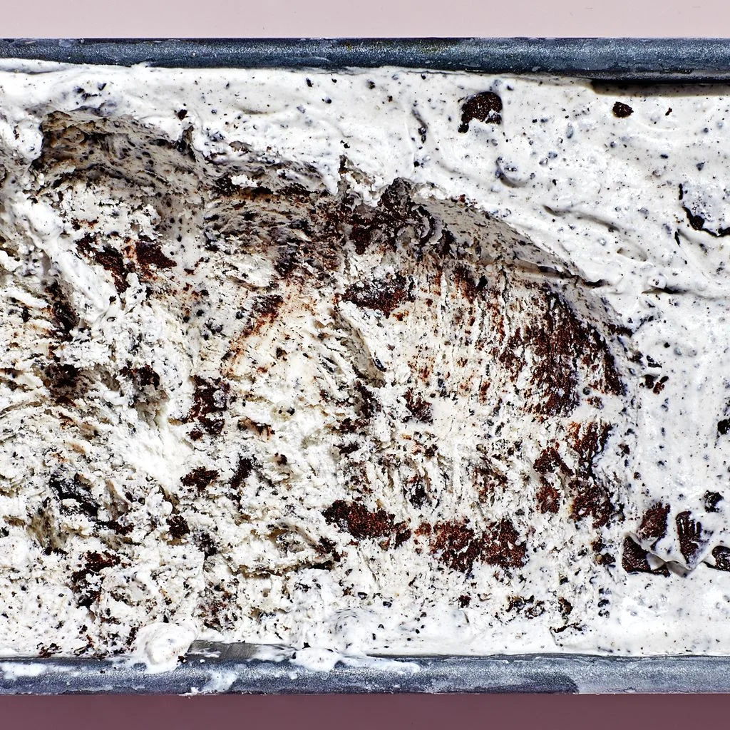 Cookies and black sesame ice cream in a metal loaf pan on a light pink background.