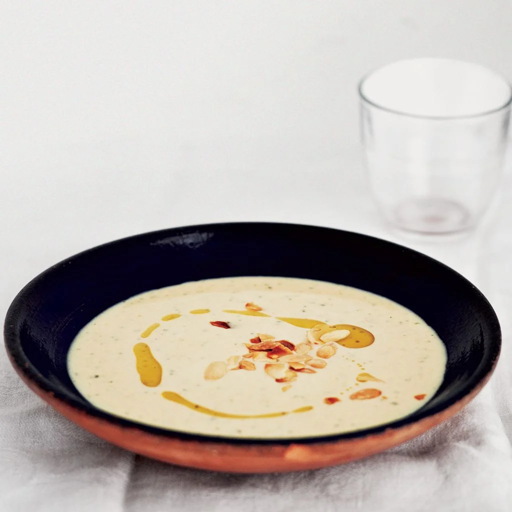 A bowl of creamy ajo blanco soup topped with toasted almonds and olive oil.
