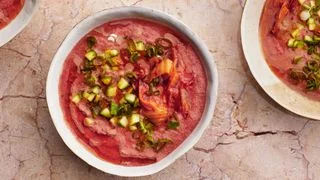 Bowl of kimchimelon gazpacho topped with chopped kimchi diced cucumber scallions and olive oil.