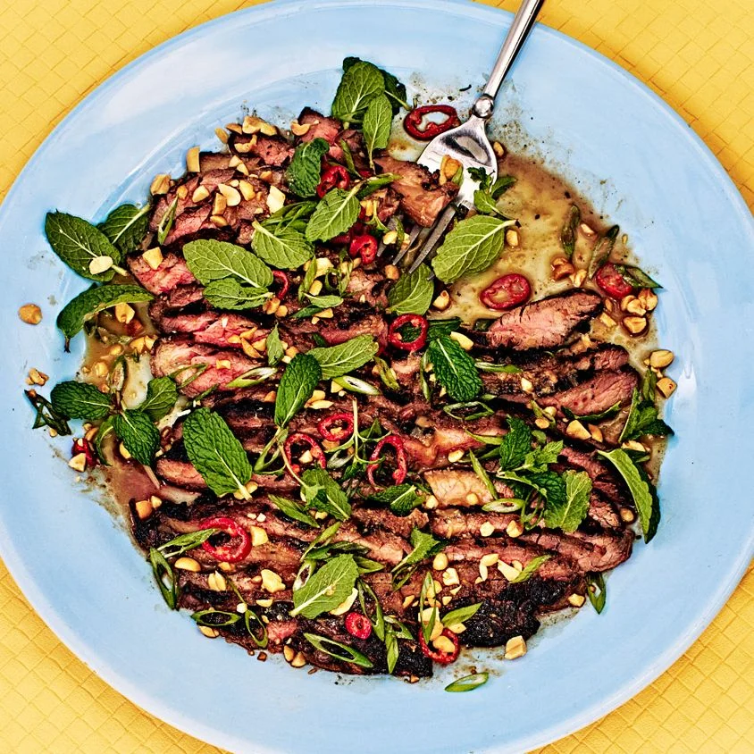 sliced steak plated in a bowl on a yellow background