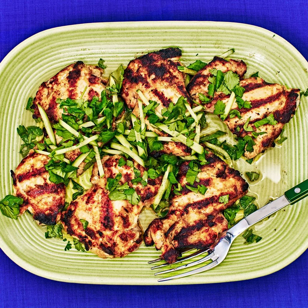 Grilled Lemongrass Chicken Thighs on a green plate placed on a blue background