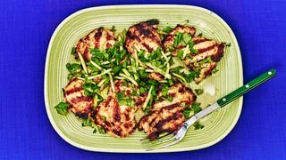Grilled Lemongrass Chicken Thighs on a green plate placed on a blue background