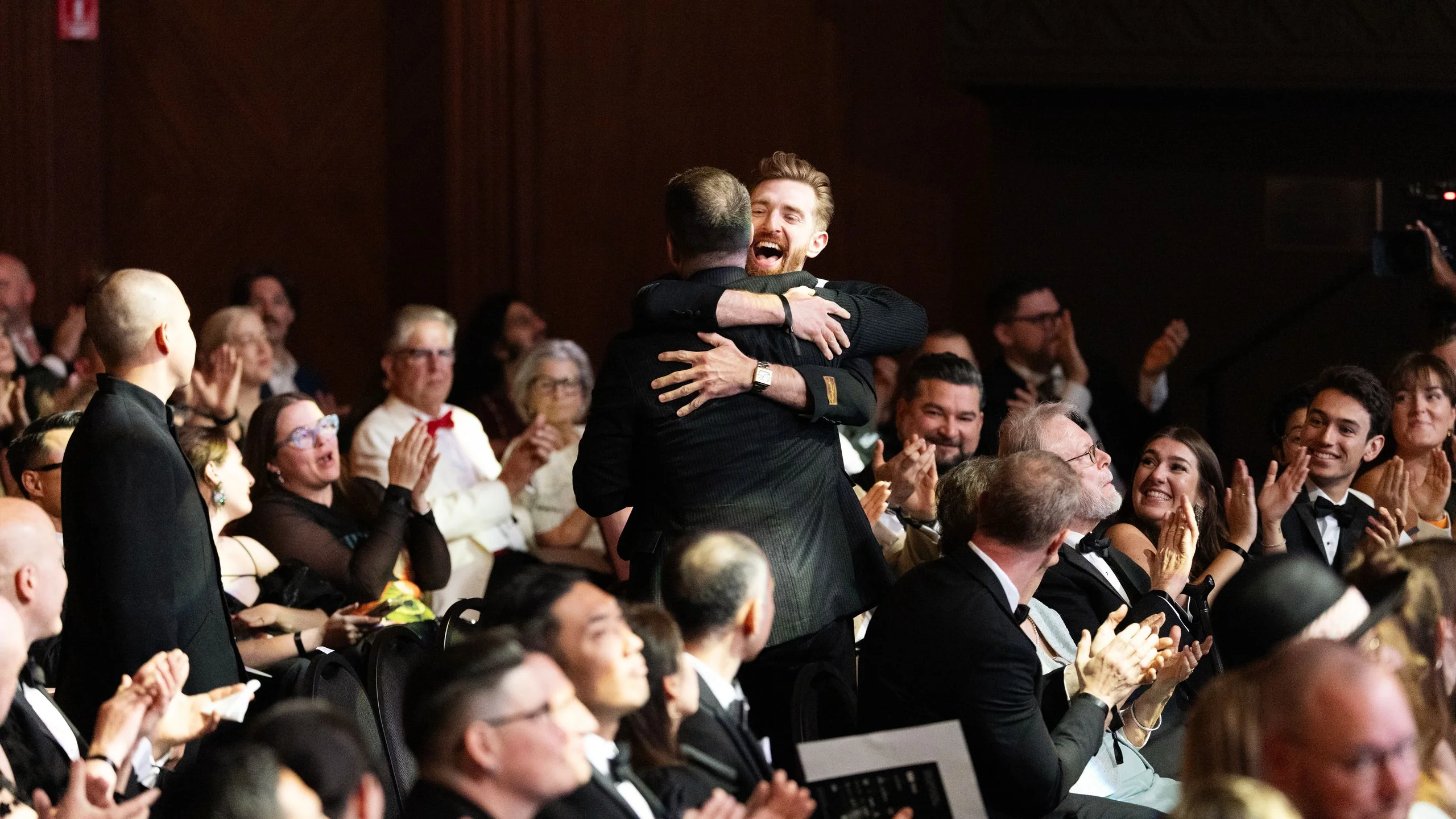 2 people hugging in the middle of crowd during an award ceremony